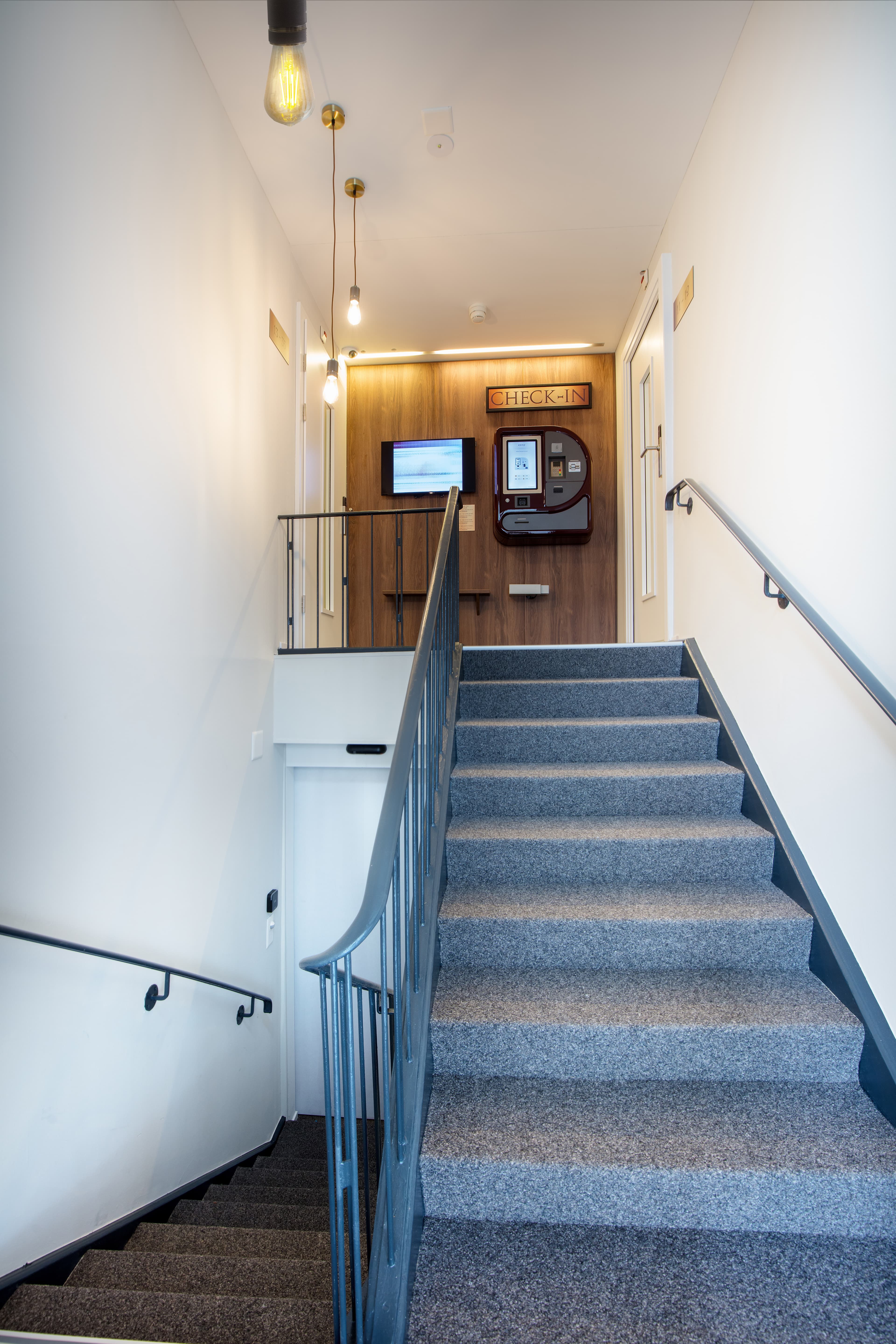 Stairs to a self check in reception at Hotel Krone with monitor and automated check in system