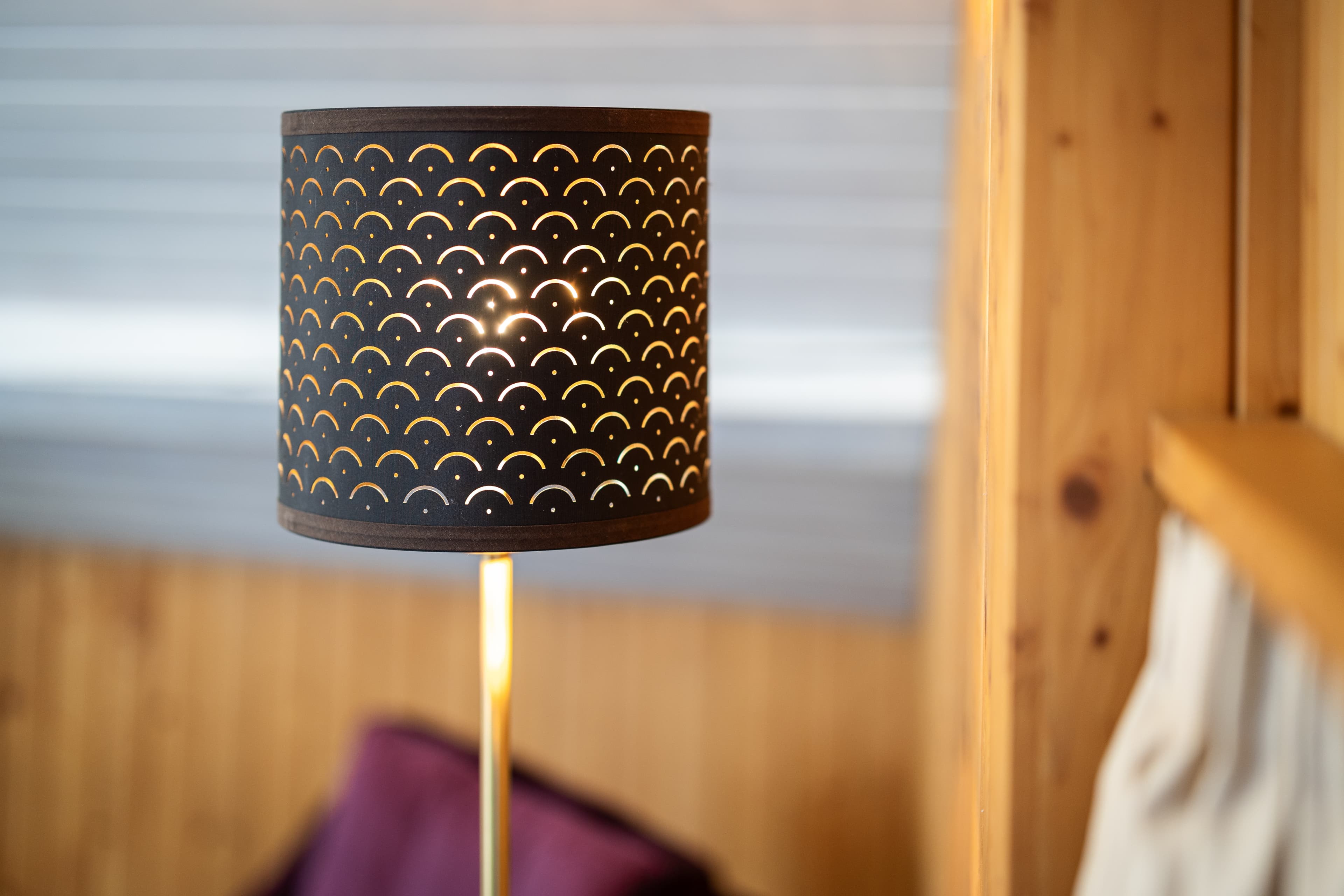 A stylish floor lamp with a decoratively perforated lampshade stands in a room of the Hotel Krone by B Smart.